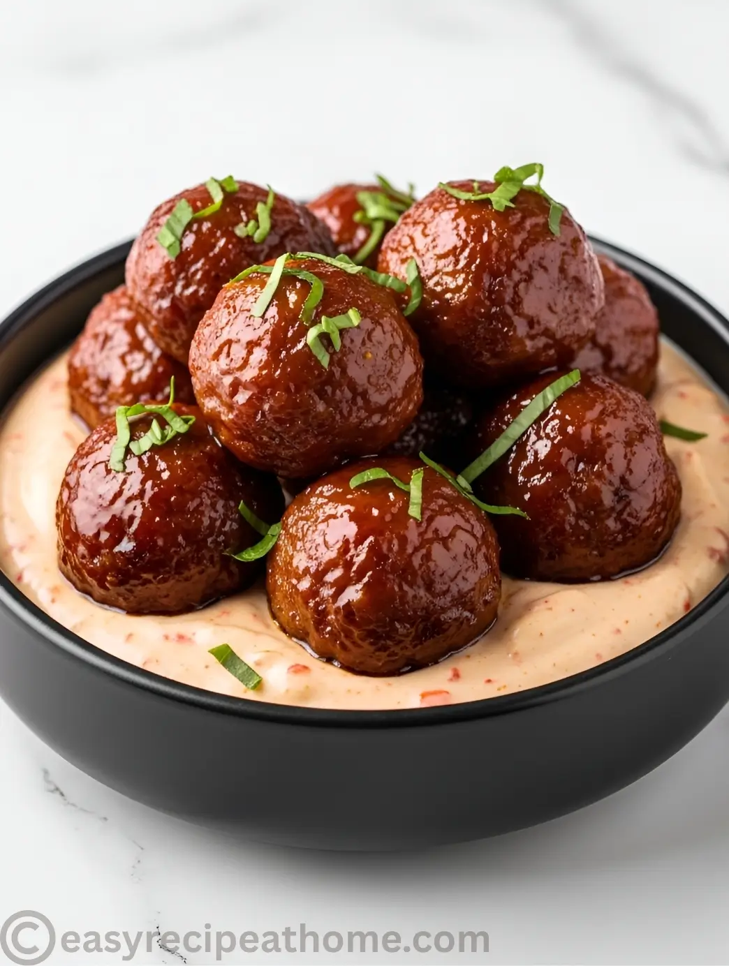 Korean BBQ meatball drizzled with spicy mayo inside a black bowl