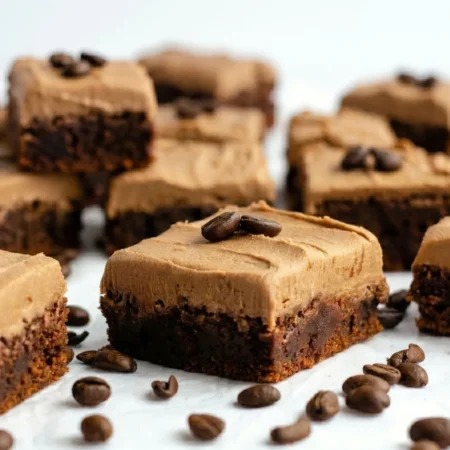 A single square slice of a fudgy coffee brownies recipe topped with a thick layer of swirled mocha buttercream on a plate.