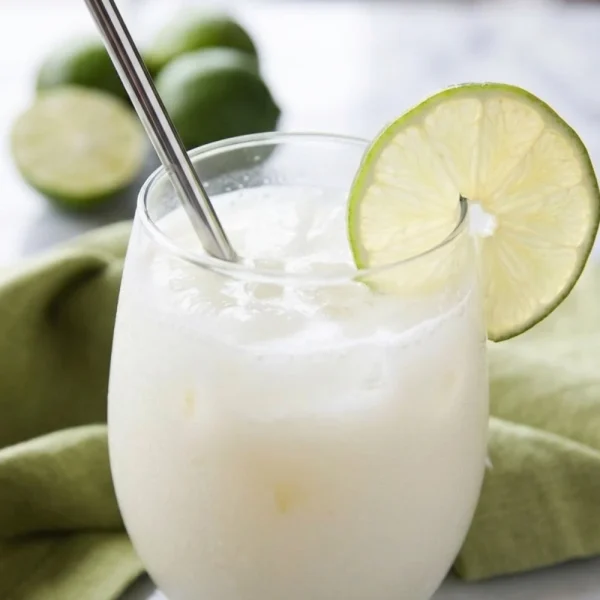 Close-up detail shot of the frothy foam and lime garnish on a glass of Brazilian lemonade, highlighting the unique texture from this Brazilian lemonade recipe.