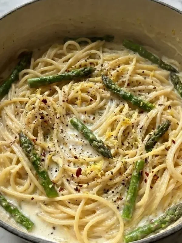 Creamy lemon garlic asparagus pasta with fresh asparagus, parmesan cheese, and herbs in a white bowl