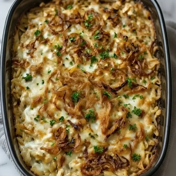 Close-up of creamy French Onion Chicken Orzo Casserole topped with crispy fried onions in a black baking dish