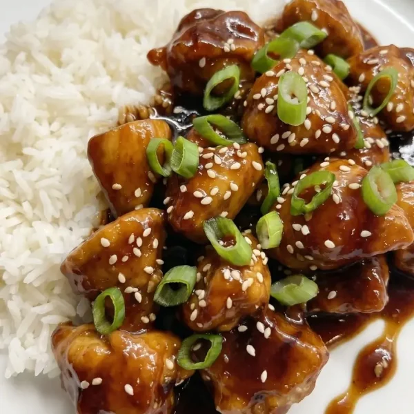One-pan Mongolian chicken served with white jasmine rice on a plate, featuring tender chicken in a glossy savory sauce.